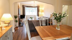 Una sala de estar acogedora con una mesa de comedor de madera, un sofá y un televisor al fondo.