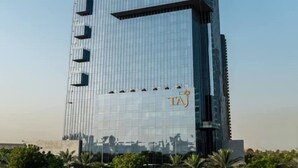 Un immeuble moderne et imposant, doté d’une façade en verre et d’un logo situé en haut.