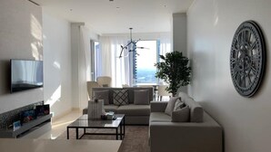 Un salon moderne avec un canapé, une table basse et un téléviseur à écran plat fixé au mur.