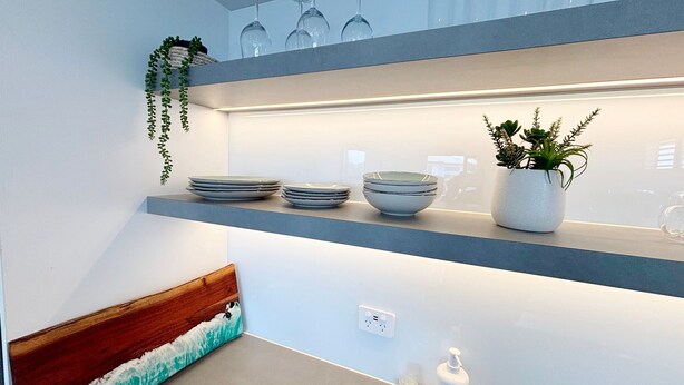 Cuina amb taulell blau, paret blanca i una planta penjant.