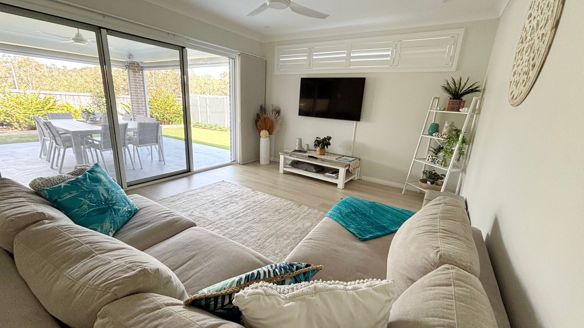 Una sala de estar con sofá, televisor de pantalla plana, mesa de centro y puerta corrediza de vidrio que da a un patio exterior.