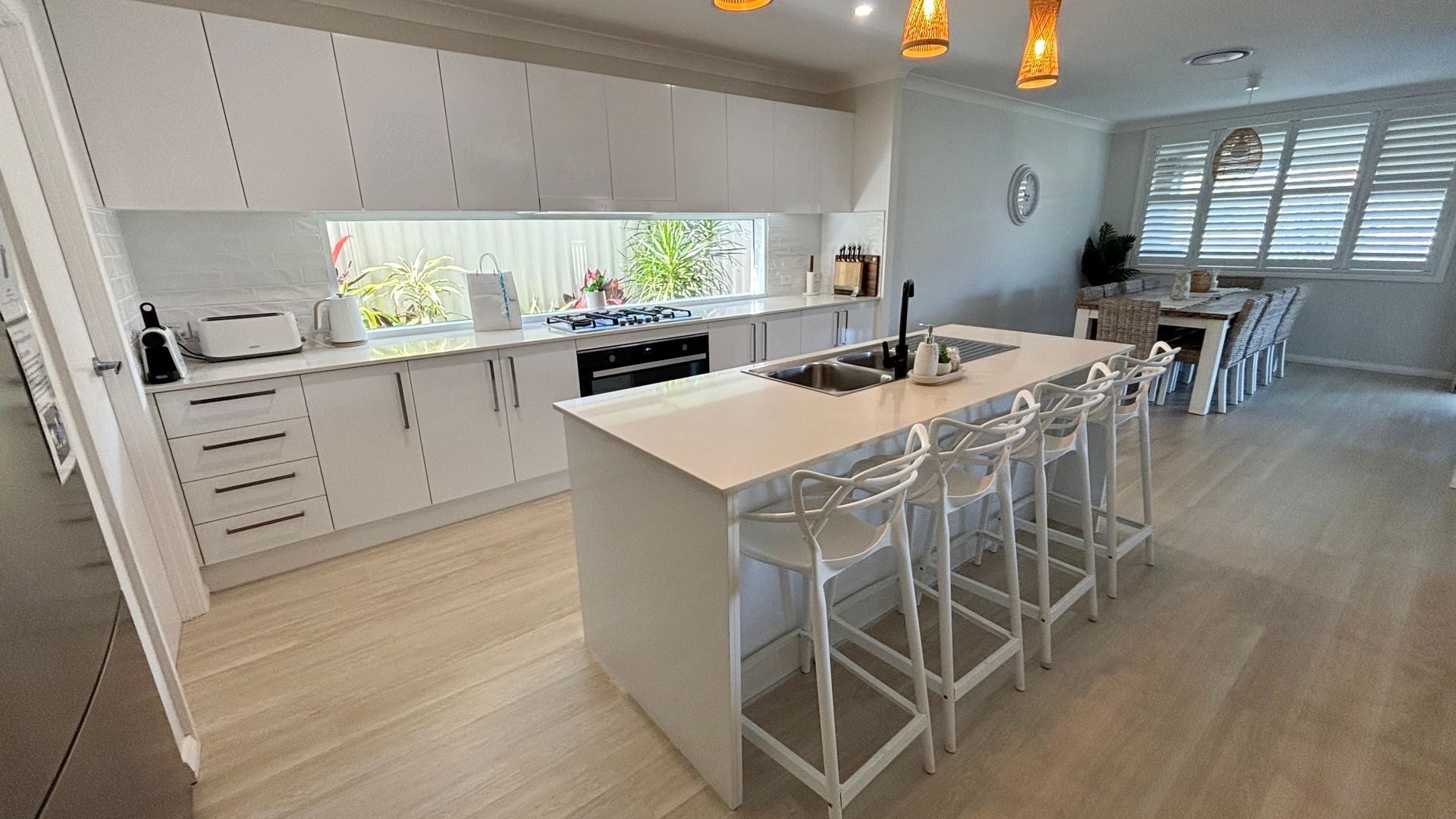 A modern kitchen with a central island, bar stools, and a dining area with a long table.