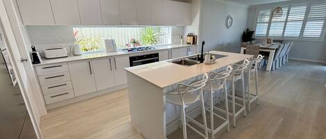 A modern kitchen with a central island, bar stools, and a dining area with a long table.