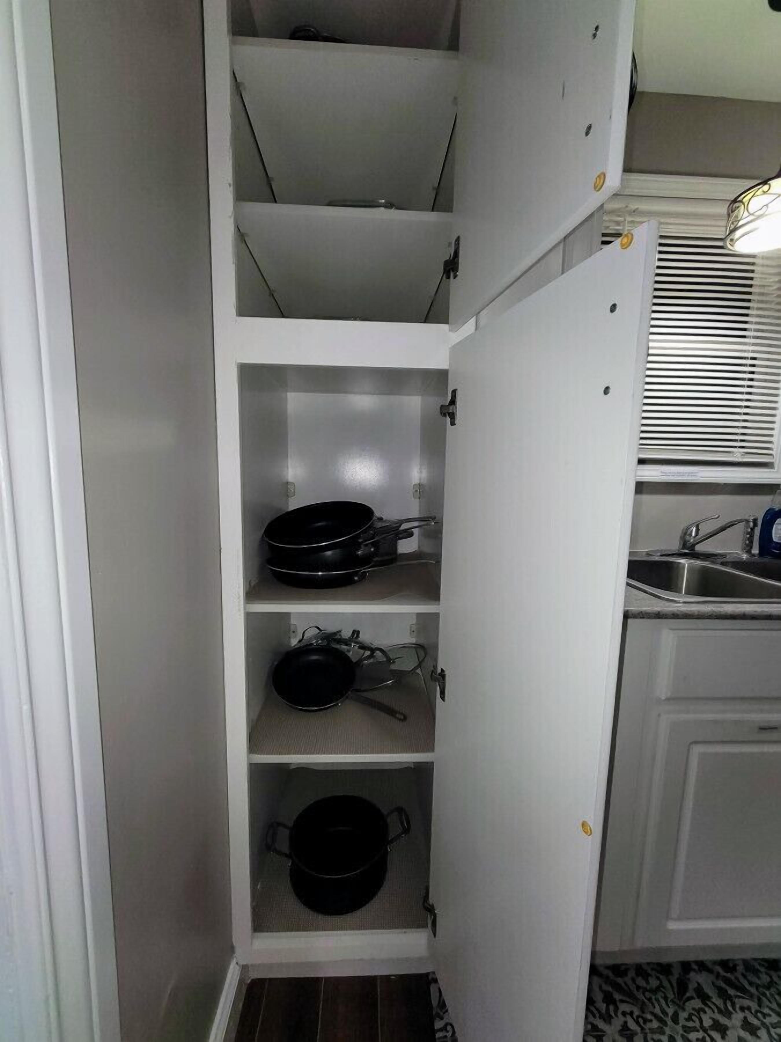 A kitchen with white cabinets, a built-in oven, and a window with blinds.