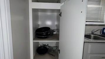 A kitchen with white cabinets, a built-in oven, and a window with blinds.