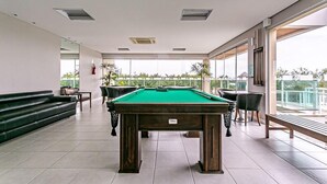Ein Billardtisch in einem großzügigen Raum mit Balkon und großen Fenstern.