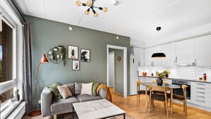 A modern living room with a grey sofa, a coffee table, and a dining area with a wooden table and chairs. - Helt ny Leilighet i Oslo Helsfyr (Oslo)
