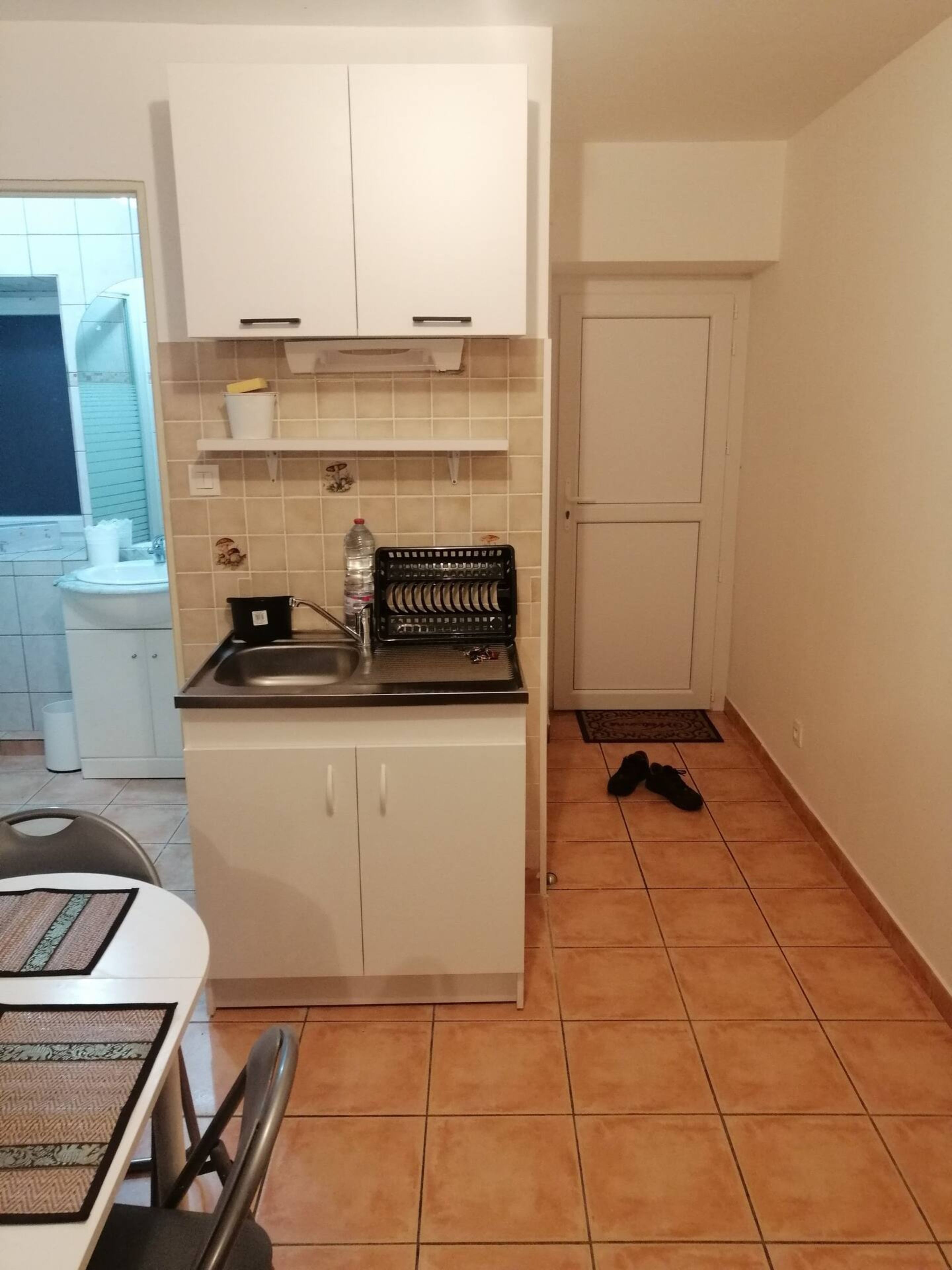 A compact kitchen with white cabinets, a sink, and a tiled backsplash.