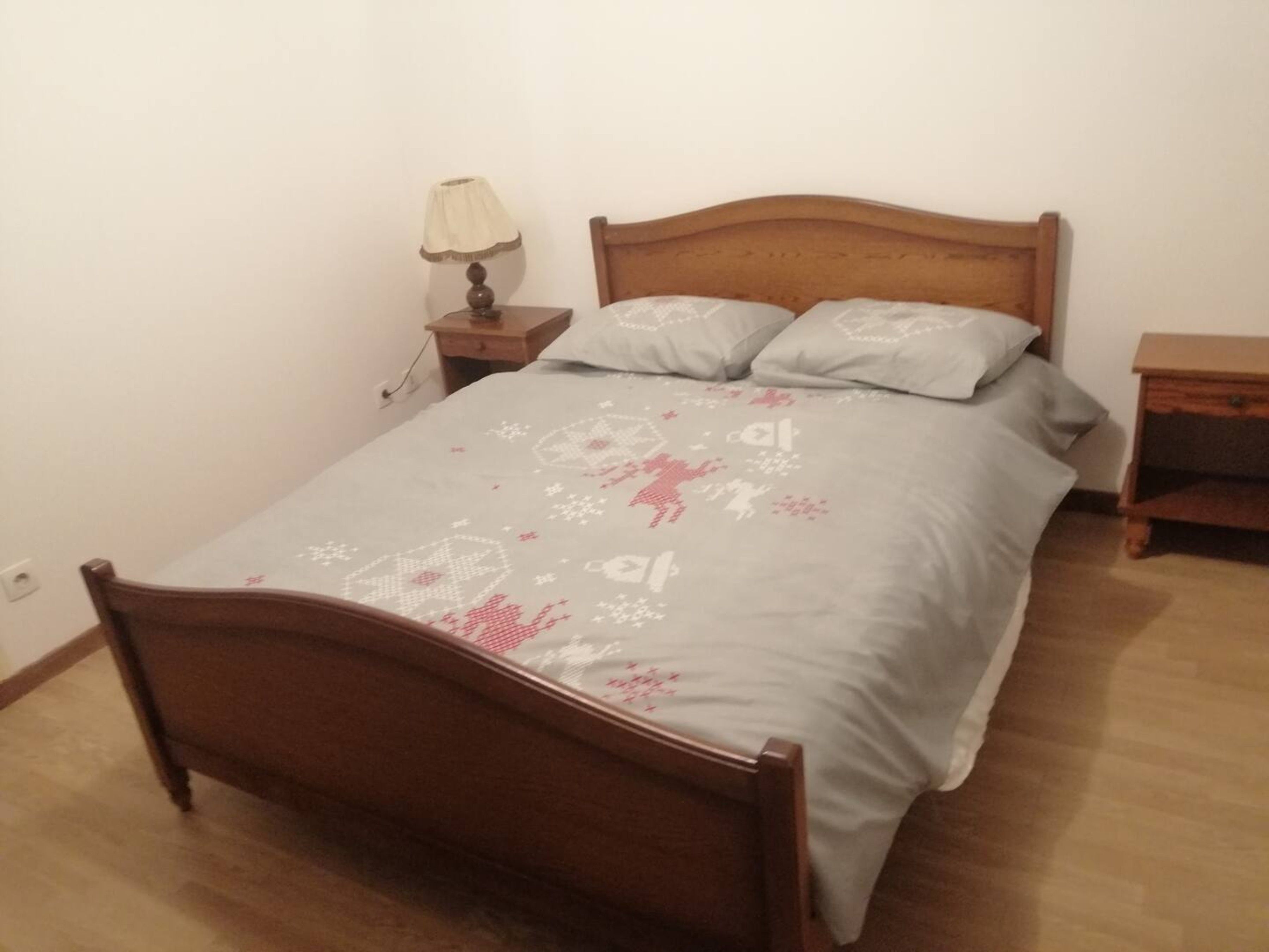 A single bed with a wooden headboard, a bedside table with a lamp, and a nightstand with a lamp.