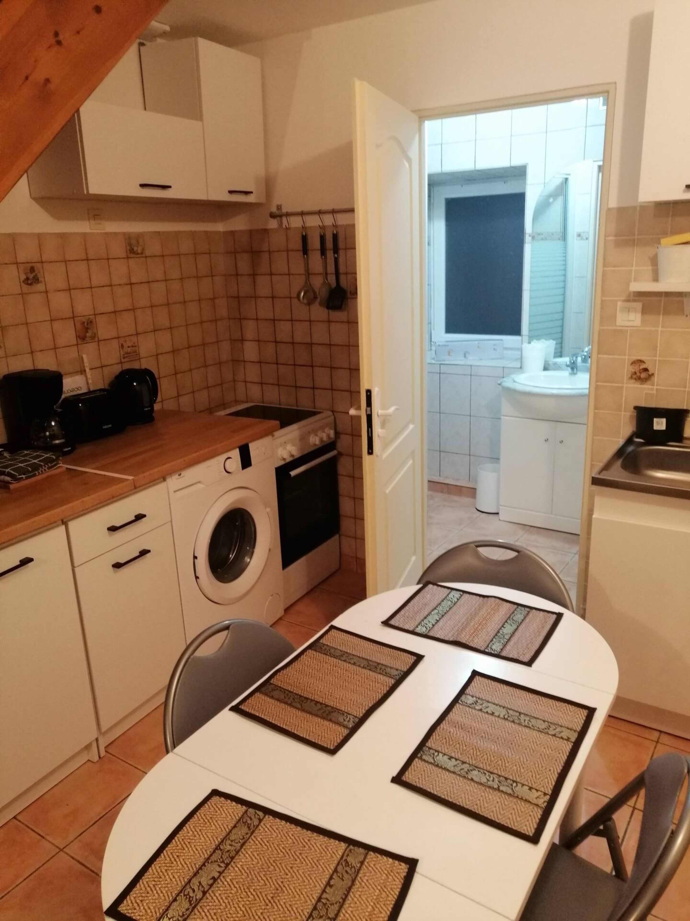 A compact kitchen with a washing machine, a coffee maker, and a sink.