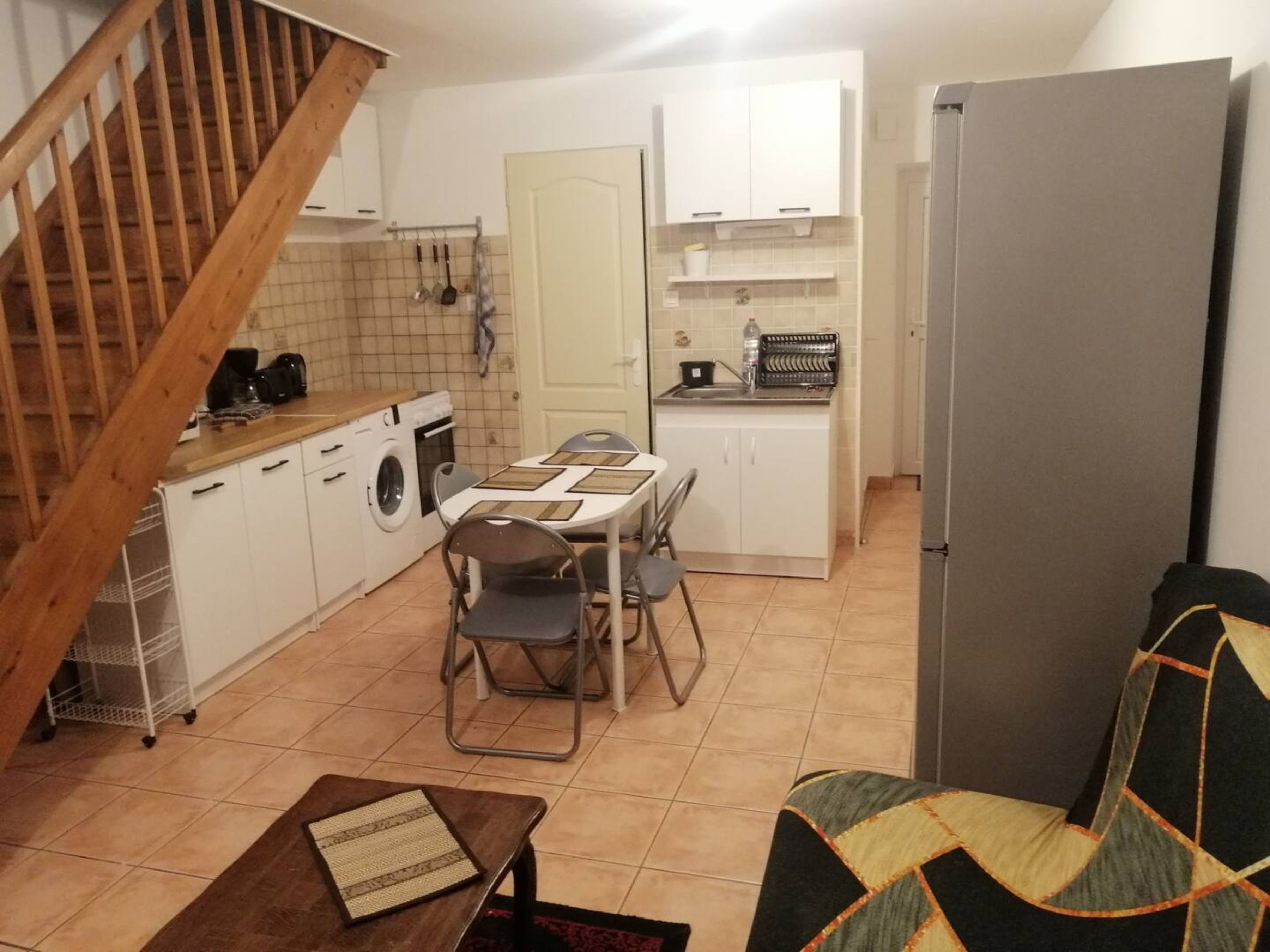 A compact kitchen with a dining area, a washing machine, and a refrigerator.