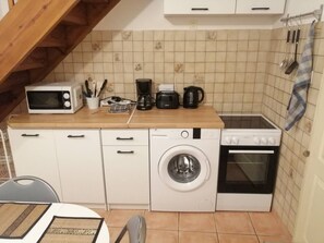 Une cuisine compacte équipée d’un four à micro-ondes, d’une machine à café, d’une bouilloire, d’un lave-linge et d’un four.