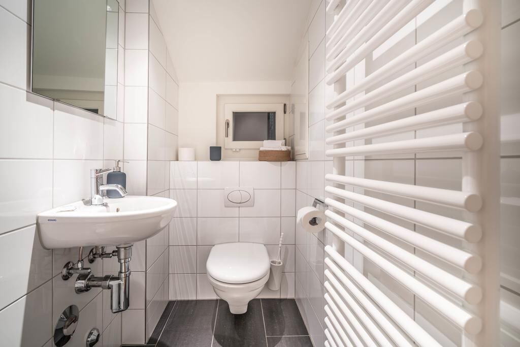 A modern bathroom with a white sink, toilet, and a towel rack.