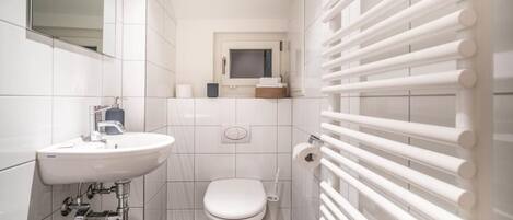 A modern bathroom with a white sink, toilet, and a towel rack.