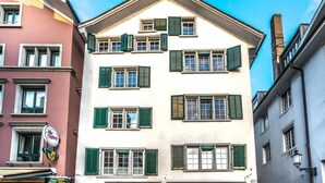 A multi-story building with green shutters, a sign for Bufalini, and a street lamp.