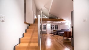 A modern interior with a wooden staircase leading to a living area with a sofa and a coffee table.