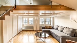 A spacious living room with a wooden staircase, a grey sofa, and a round coffee table.