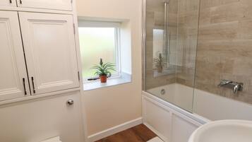 Ein Badezimmer mit Dusche, Toilette und einem Fenster mit Pflanze.