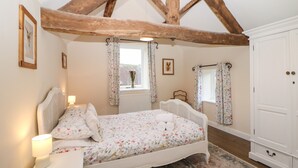 Ein Schlafzimmer mit Bett, Nachttisch und einem Fenster mit Vorhängen.
