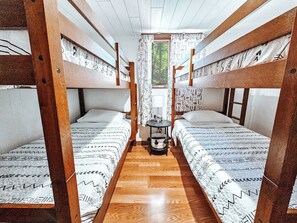 Eine Hütte mit zwei Etagenbetten, einem kleinen Tisch mit Lampe und einem Fenster mit Vorhängen.