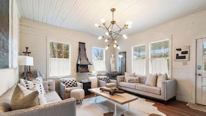 A spacious living room with a fireplace, a chandelier, and a cowhide rug.