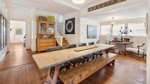 A spacious dining area with a long wooden table and benches, a staircase leading to another room, and a sign that reads "CROSSING" on the wall.