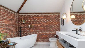 A modern bathroom with a freestanding bathtub, a white sink, and a large mirror. - Inkwell Suite at Spofford Lodge (Bucksport)