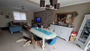 Een eethoek met een ronde tafel, blauwe stoelen en een hond die op de vloer ligt.