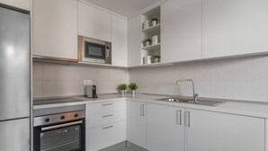A modern kitchen with white cabinets, a built-in microwave, a coffee maker, and a stainless steel sink. - GO2TENERIFE Apart'Jara Pool view & Beach at 5 min (Playa de las Americas)