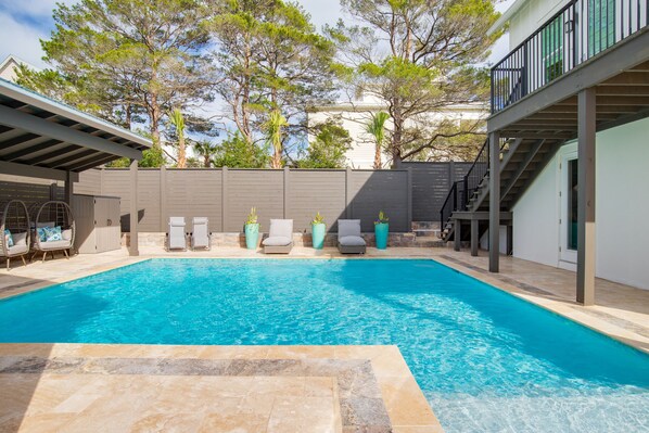 Une piscine avec des chaises longues et un espace patio couvert.