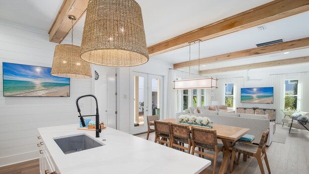 Une cuisine moderne avec un plan de travail blanc, des chaises en bois et une table à manger.