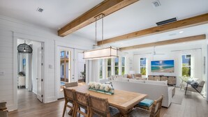Une cuisine spacieuse avec des poutres en bois, un coin repas avec une table et des chaises en bois, et un salon avec un canapé et un téléviseur.