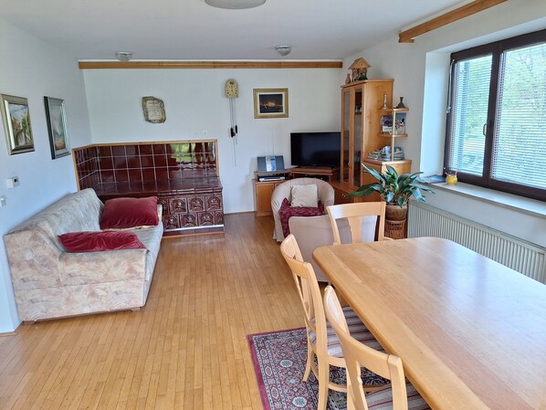 Un salon comprenant un canapé, une table à manger, des chaises, un téléviseur, un meuble et une fenêtre.
