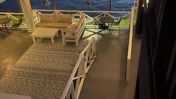 Een terras met een patroon in de vloer, witte meubels en lichtslingers.
