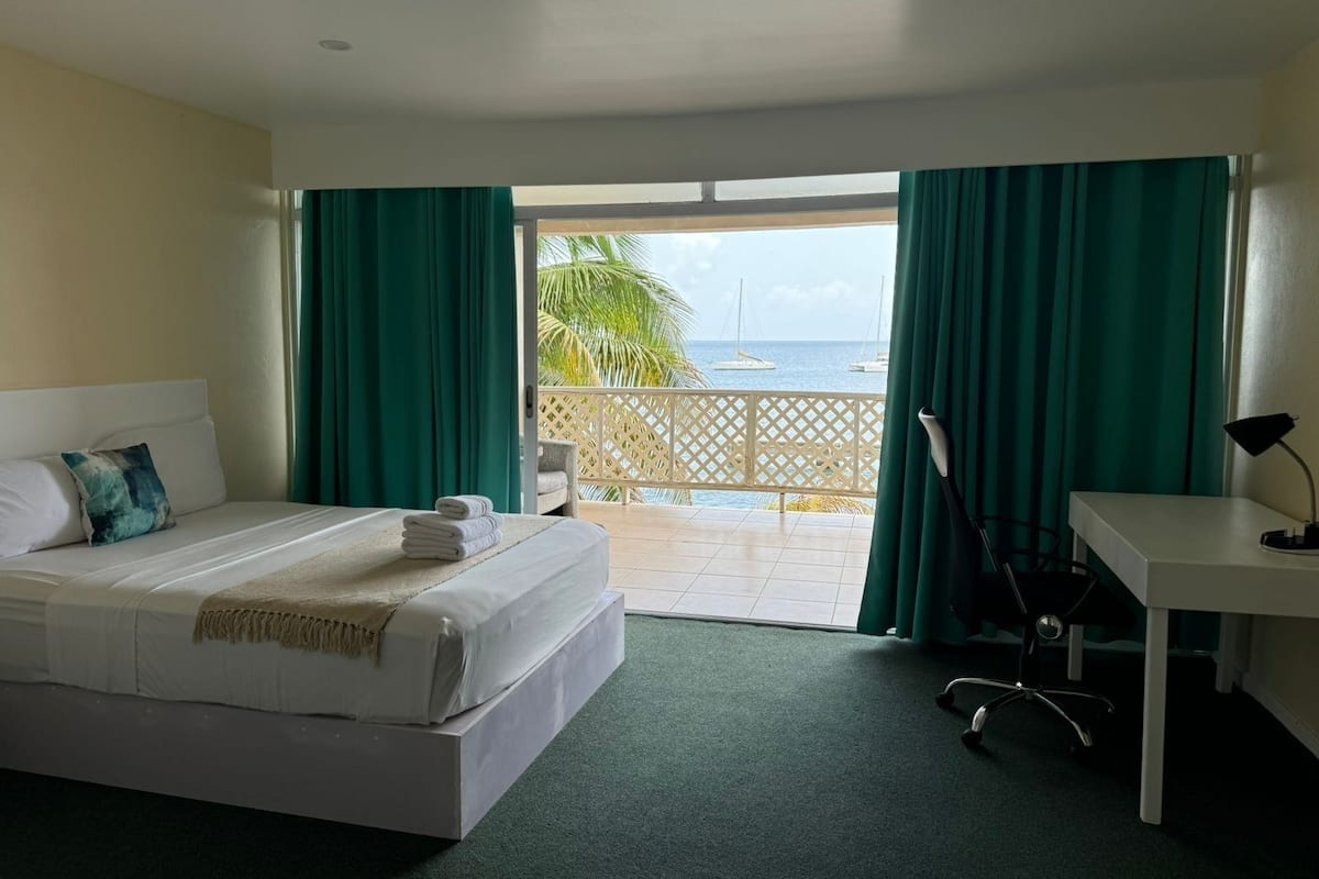 Una habitación de hotel con cama, escritorio y vista al mar.