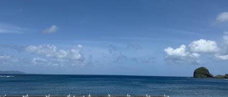 A pier extending into calm blue waters with a clear sky and a small island in the distance.