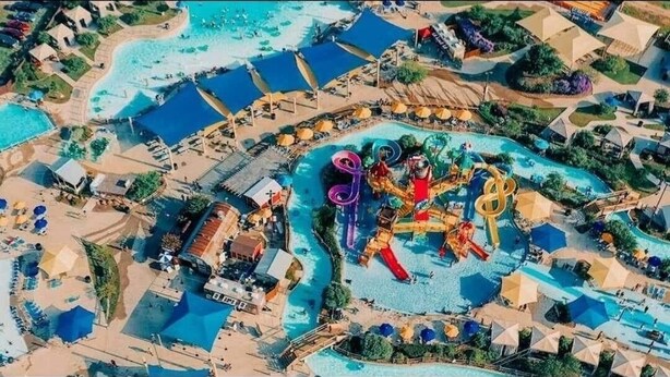 Luchtbeeld van een resort met meerdere zwembaden, glijbanen en een centraal gelegen gebied met een groot waterattractie.