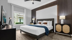 Una camera da letto moderna con un letto, lampade da comodino, una scrivania e vista sul verde circostante.