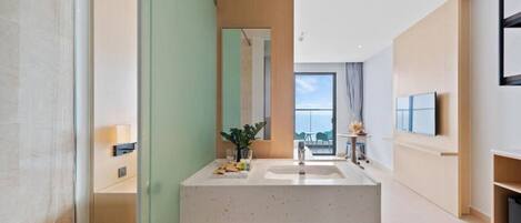 A modern bathroom with a large mirror, a sink, and a shower area.