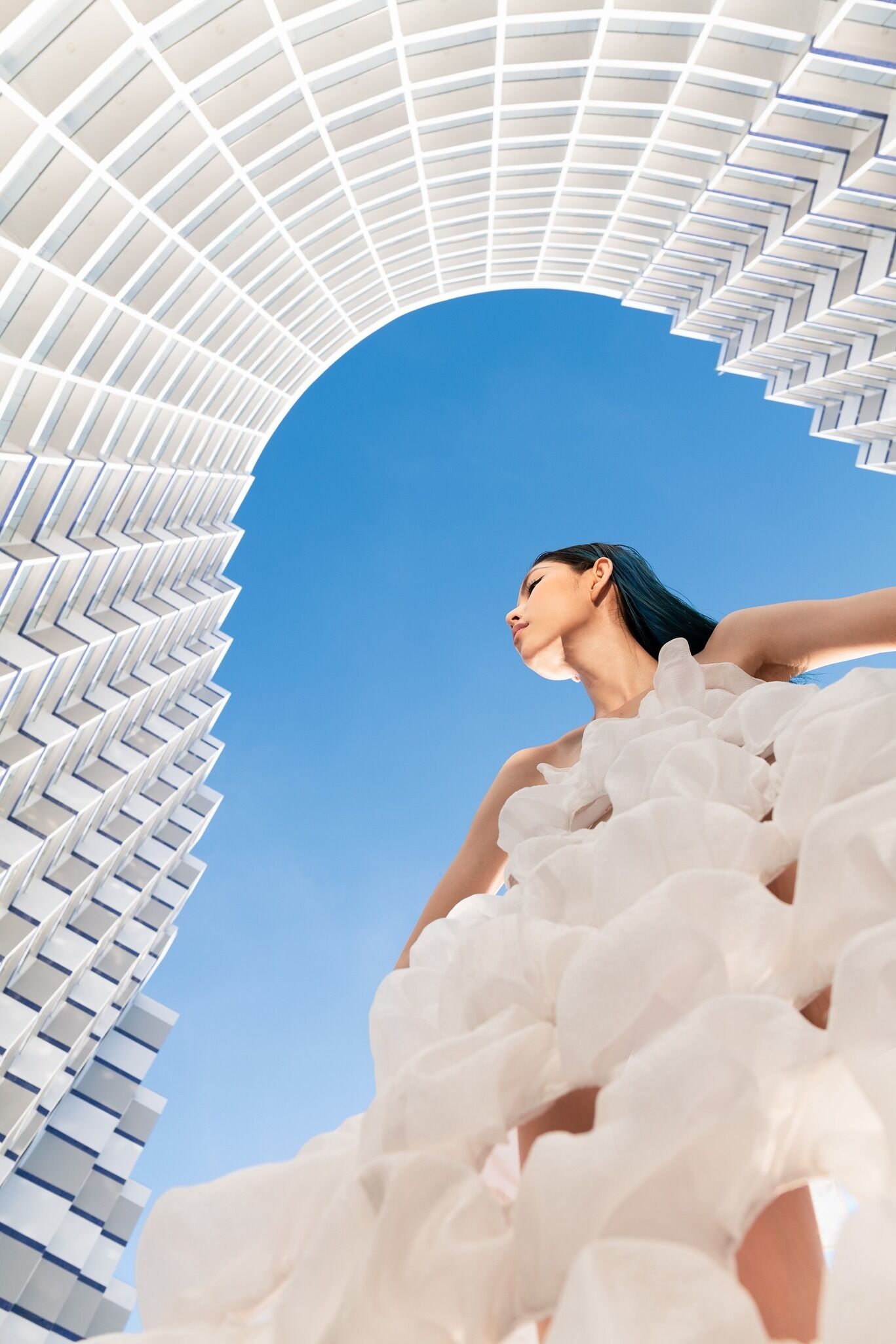 Une structure architecturale moderne, dotée d’un design géométrique, avec un ciel bleu clair en arrière-plan.