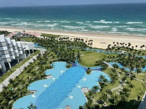A resort with a large central pool, a beach, and palm trees. - K' Sea View Resort Cam Ranh (Bac Cam Ranh)