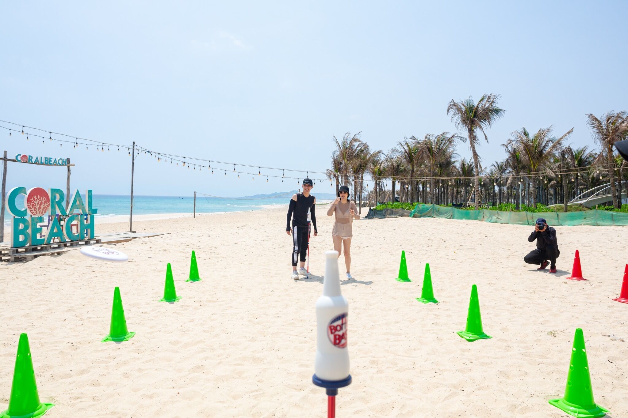 A beach with a sign reading "CORAL BEACH" and several people walking.