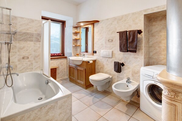 A bathroom with a bathtub, sink, toilet, bidet, and washing machine. - Apartment 'Premesan 5' with Wi-Fi (Bormio)