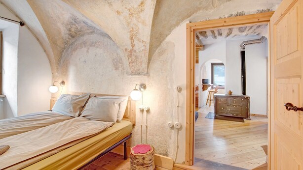 A bedroom with a wooden bed, a small stool, and a wooden wardrobe. - Apartment 'Premesan 5' with Wi-Fi (Bormio)