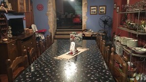 A dining room with a wooden table and chairs, a television, and a fan. - Casa Rural El Salidero en Fuentidueña (Fuentidueña)