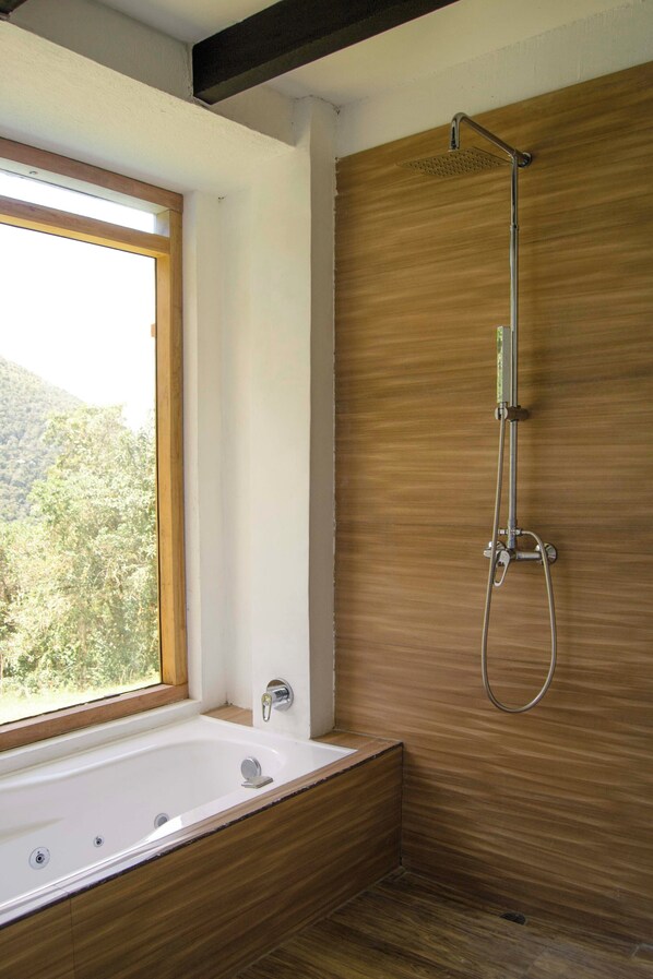 A modern bathroom with a wooden vanity, a freestanding bathtub, and a shower with a handheld showerhead. - Neblina Bird (Plaza Gutiérrez)
