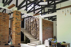 Un interior moderno con paredes de ladrillo visto, una escalera y un comedor con mesa y sillas.