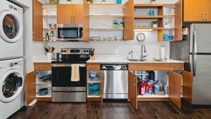 A compact kitchen with built-in appliances, wooden cabinets, and open shelving.