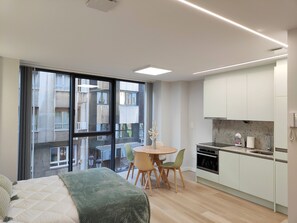 A modern apartment with a large window, a dining area, and a kitchenette. - Loft Moderno, Céntrico y Acogedor (Oviedo)