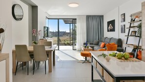 Un espacio habitable moderno con comedor, cocina y zona de estar con vistas a la ciudad.